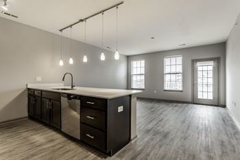 An empty living room with an island in the center of it and a large kitchen